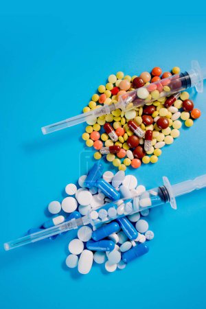 Photo for Two medical syringes with pills and randomly scattered pills of different colors and sizes. Treatment concept. - Royalty Free Image