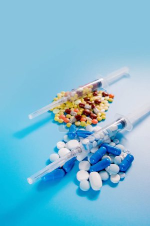 Photo for Two medical syringes with pills and randomly scattered pills of different colors and sizes. Treatment concept. - Royalty Free Image