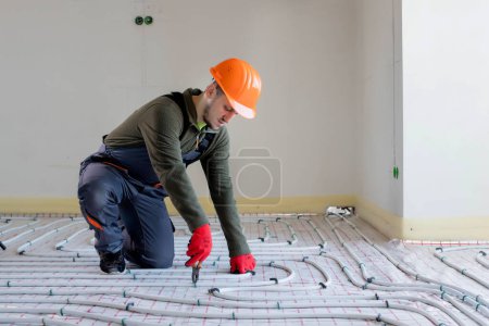 Photo for Worker is installing underfloor heating system. Warm floor heating system. - Royalty Free Image