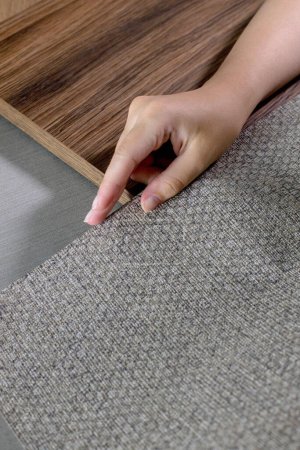 Photo for The choice of finishing materials for the design of the house project. The hand of an interior designer selects a palette of sample materials for wallpaper and chipboard panels. - Royalty Free Image