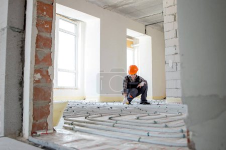 Photo for Woman worker takes measurements during the installation of a warm floor. Warm floor heating system. - Royalty Free Image