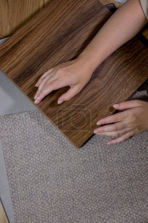 Photo for The choice of finishing materials for the design of the house project. The hand of an interior designer selects a palette of sample materials for wallpaper and chipboard panels. - Royalty Free Image