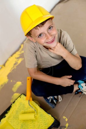 Photo for Cute boy with a paint roller. Happy kid helps parents to paint wall. New house for family - Royalty Free Image