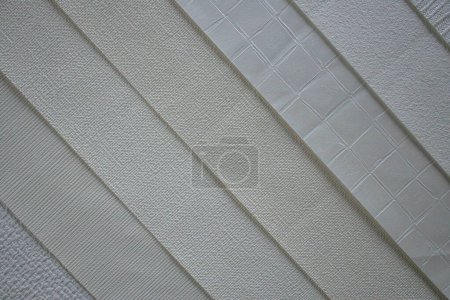 Foto de Una colección de muestras de papel pintado interior en tonos beige texturizados. Material de élite para revestimiento de paredes. - Imagen libre de derechos