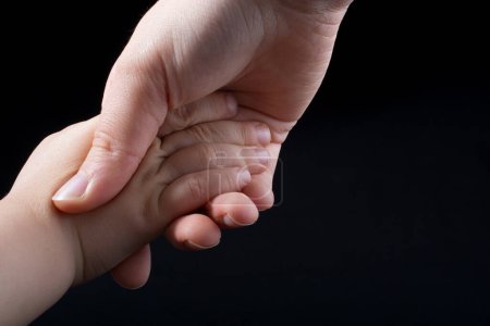 Foto de Adulto y niño tomados de la mano en fondo negro - Imagen libre de derechos