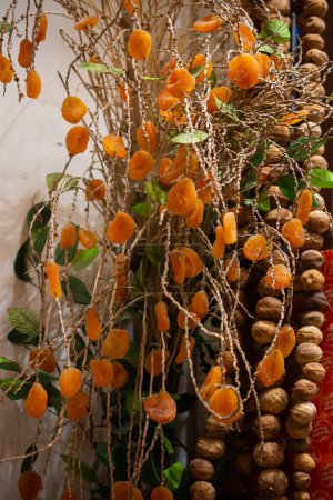 Téléchargez les photos : Abricots secs suspendus à une branche d'arbre près d'un marché - en image libre de droit