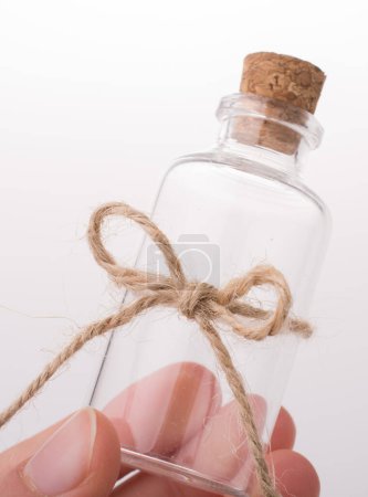 Téléchargez les photos : Petite bouteille en verre vide à la main sur fond blanc - en image libre de droit