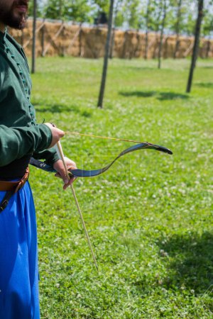Téléchargez les photos : Archer avec arc en vêtements traditionnels tirant une flèche - en image libre de droit