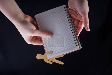 Foto de Forma de hombre cortada de papel en cuaderno en mano - Imagen libre de derechos