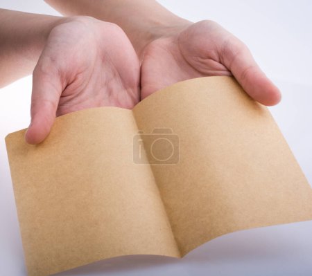 Photo for Hand holding a brown color sheet of paper on a white background - Royalty Free Image