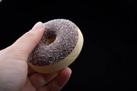 Photo for Hand holding a Fake plastic donuts in black background - Royalty Free Image