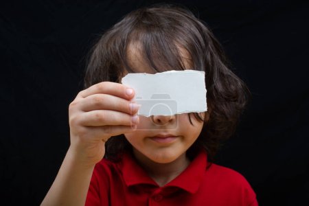 Téléchargez les photos : Petit garçon mignon tenant un papier déchiré sur sa bouche - en image libre de droit