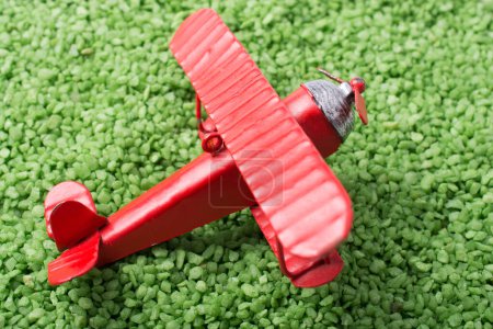 Téléchargez les photos : Avion jouet de couleur rouge est sur une texture de sable - en image libre de droit