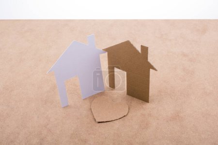Téléchargez les photos : Icône en forme de coeur et maisons en papier sur un fond brun - en image libre de droit