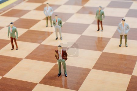 Foto de Figura de personas en miniatura de pie en el tablero de ajedrez como estrategia Concepto - Imagen libre de derechos