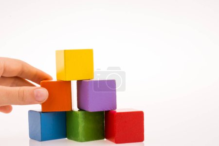 Téléchargez les photos : Jouer à la main avec des cubes colorés sur un fond blanc - en image libre de droit