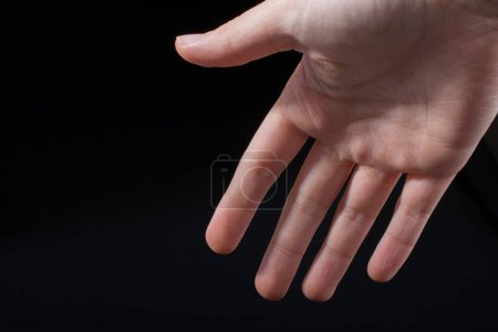 Téléchargez les photos : Cinq doigts d'une main d'enfant en partie vus en fond noir - en image libre de droit