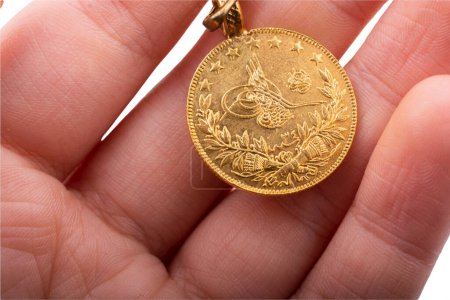 Foto de Moneda de oro estilo otomano turco en mano sobre fondo blanco. - Imagen libre de derechos