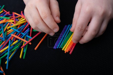 Foto de Niño jugando con palos de madera de colores para la creatividad sobre fondo blanco - Imagen libre de derechos
