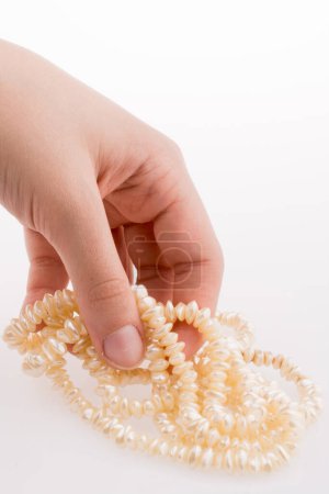 Photo for Hand holding pearl necklace on white background - Royalty Free Image