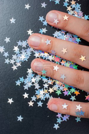 Photo for Colorful confetti  stars on a hand and dark background - Royalty Free Image