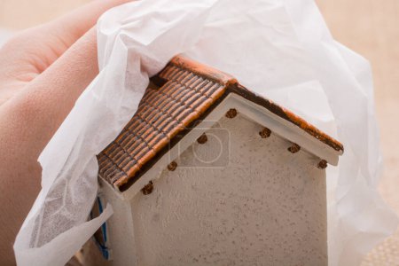 Téléchargez les photos : Petite maison modèle enveloppée dans un tissu sur un fond brun - en image libre de droit