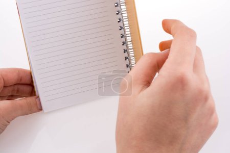 Foto de Mano sosteniendo un cuaderno sobre un fondo blanco - Imagen libre de derechos