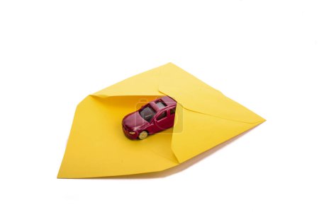 Foto de Pequeño coche rojo en un sobre amarillo - Imagen libre de derechos