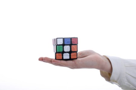 Photo for Child holding a Rubik's cube in hand on a white background - Royalty Free Image