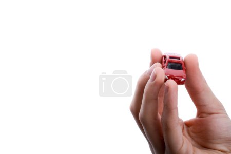 Foto de Mano de niño sosteniendo un coche rojo sobre un fondo blanco - Imagen libre de derechos