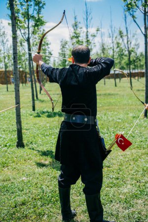 Téléchargez les photos : Archer avec arc en vêtements traditionnels tirant une flèche - en image libre de droit