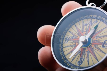 Photo for Hand is holding a magnetic compass on black background - Royalty Free Image