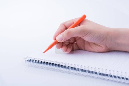 Foto de Escritura a mano en un cuaderno con un bolígrafo sobre un fondo blanco - Imagen libre de derechos