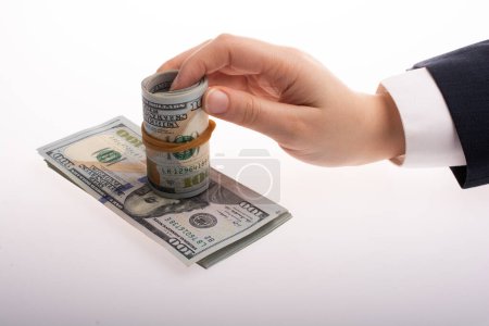 Téléchargez les photos : Un homme tient dans sa main de l'argent (dollars américains) dans un rouleau attaché avec un groupe - en image libre de droit