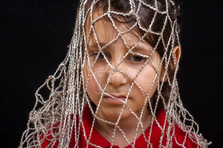 Téléchargez les photos : Petit garçon piégé dans un filet comme captivité - en image libre de droit