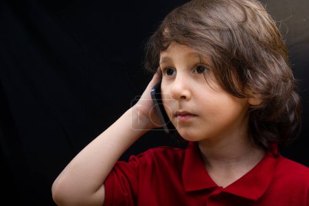 Téléchargez les photos : Petit garçon tenir smartphone comme gadget de communication mobile moderne - en image libre de droit