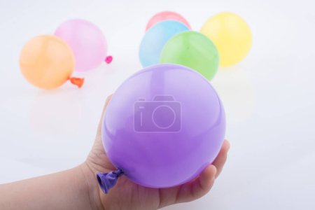 Foto de Mano sosteniendo un colorido globo pequeño con globos de colores sobre el fondo blanco - Imagen libre de derechos