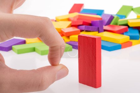 Foto de Mano jugando con dominó de color sobre fondo blanco - Imagen libre de derechos