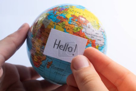 Photo for Hand holding notepaper with HELLO wording on model globe - Royalty Free Image