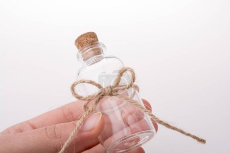 Téléchargez les photos : Petite bouteille en verre vide à la main sur fond blanc - en image libre de droit