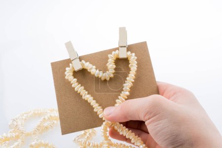 Téléchargez les photos : Collier de perles forme une forme de coeur sur papier sur fond blanc - en image libre de droit