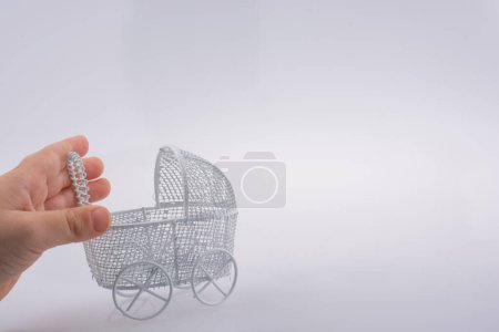Foto de Coche de bebé de juguete en mano de metal sobre fondo blanco - Imagen libre de derechos
