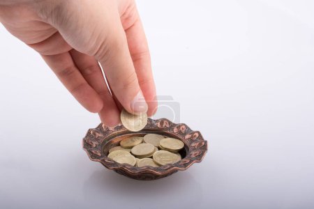 Photo for Hand giving away money to a metal bowl - Royalty Free Image