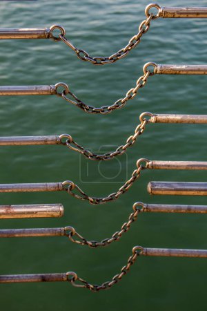 Téléchargez les photos : Chaîne relie deux barres métalliques sur un plan d'eau - en image libre de droit