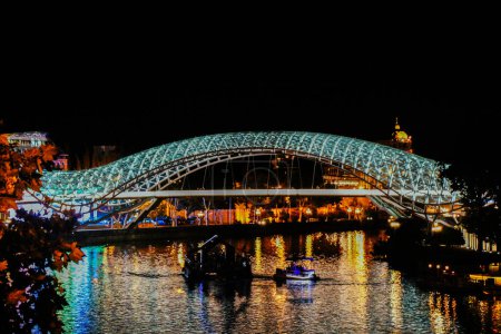 Téléchargez les photos : Le Pont de la Paix est une passerelle piétonne en forme d'arc, une construction en acier et en verre éclairée par de nombreuses LED, à Tbilissi - en image libre de droit
