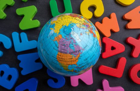 Téléchargez les photos : Globe terrestre modèle sur lettres colorées sur un fond noir - en image libre de droit