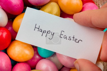 Foto de Feliz Pascua escrita en un pequeño trozo de papel sobre rocas decorativas de colores en exhibición - Imagen libre de derechos
