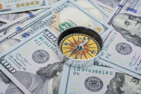 Foto de Concepto de dirección económica con brújula en billetes en dólares - Imagen libre de derechos