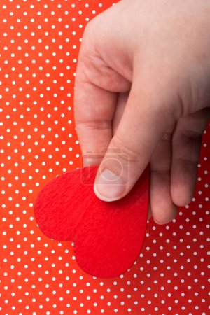 Photo for Red color heart shaped object in hand  on dotted paper - Royalty Free Image