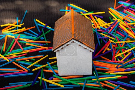 Téléchargez les photos : Petite maison modèle sur petits bâtons colorés éparpillés - en image libre de droit
